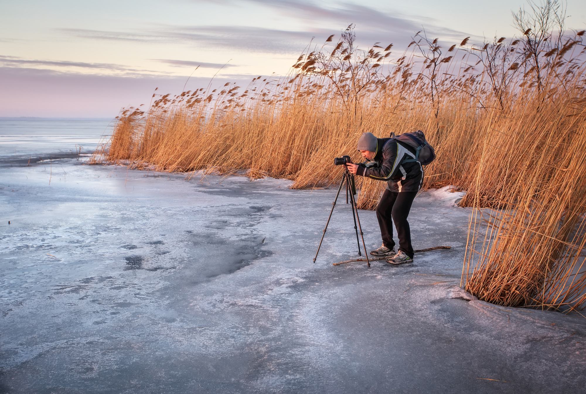 Photographer takes a picture of sunset on a frozen lake